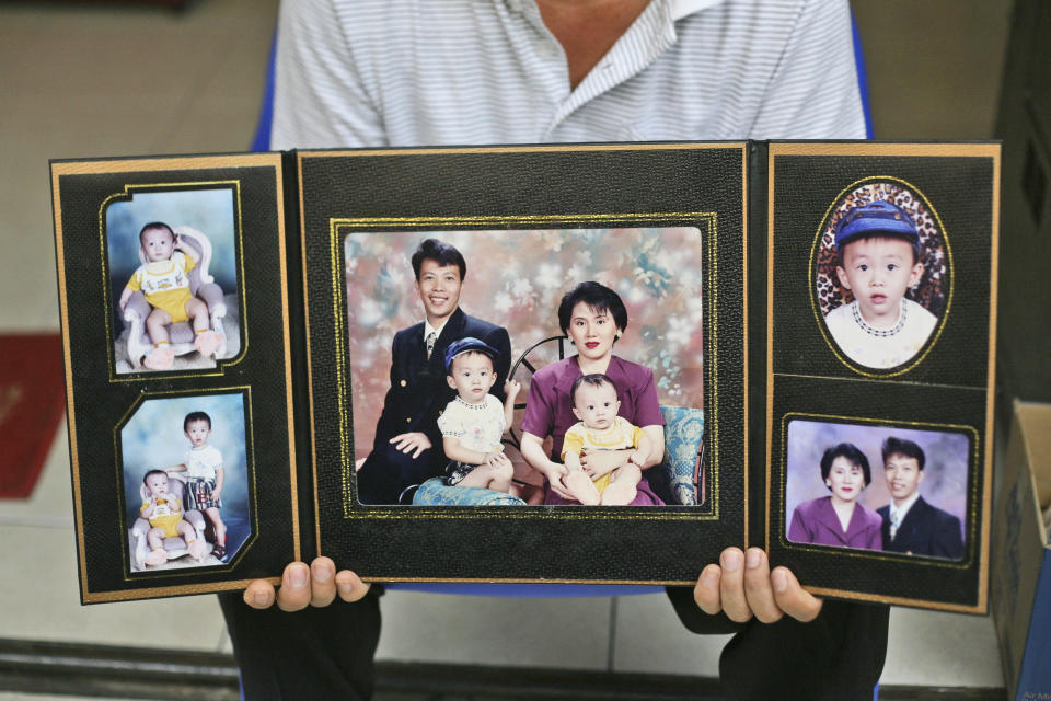 FILE - In this Tuesday, March 25, 2014 file photo, a relative holds family portraits of Sugianto Lo, who was onboard the missing Malaysia Airlines Flight 370, with his wife Vinny, in Medan, North Sumatra, Indonesia. Indonesians Sugianto Lo and his wife, Vinny Chynthya Tio, were taking a short break away from their three children, their first in more than 17 years as parents. It was hard. Family members had to convince them the children would be fine while they were gone. (AP Photo/Binsar Bakkara, File)