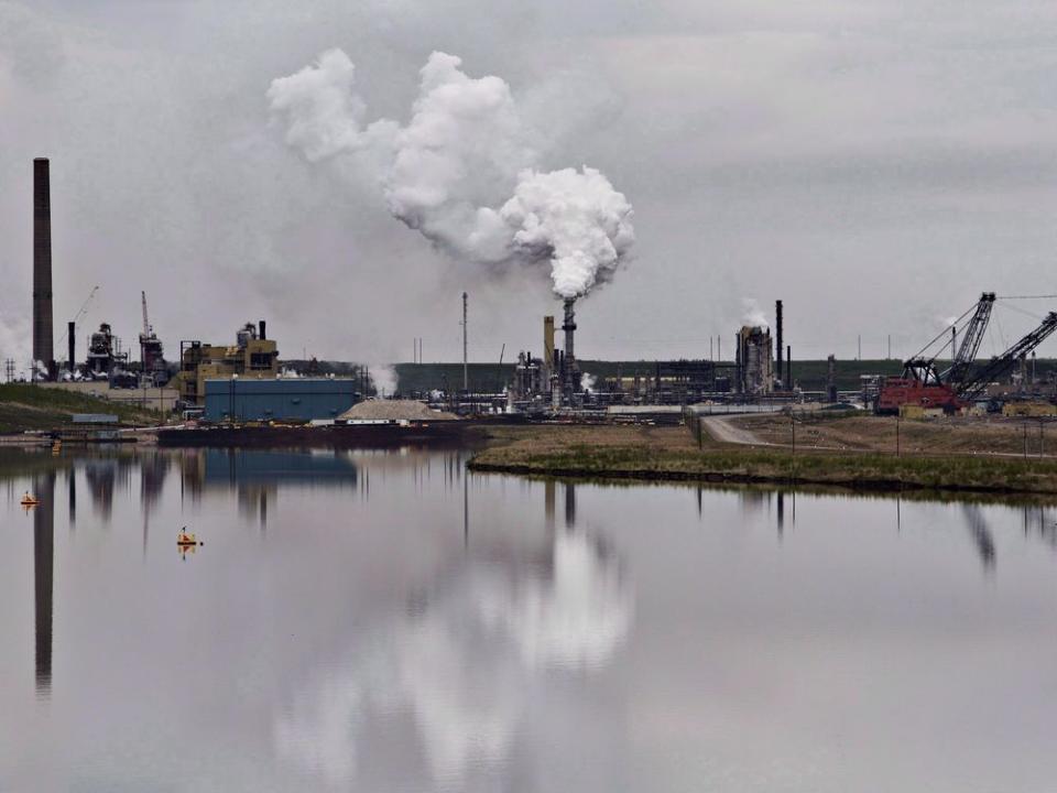  The Syncrude oil sands extraction facility is reflected in a tailings pond near Fort McMurray, Alta.