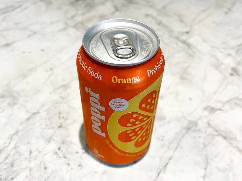 An unopened can of orange Poppi on a countertop.