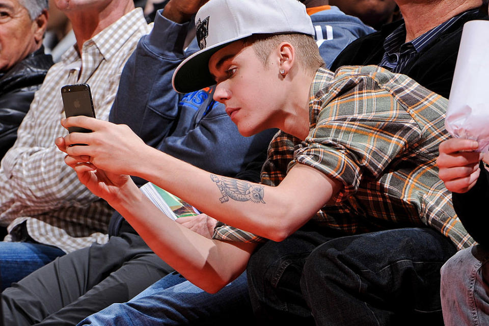 LOS ANGELES, CA – DECEMBER 27: Recording artist Justin Bieber takes a picture using an Apple Inc. iPhone 5 during a game between the Boston Celtics and Los Angeles Clippers on December 27, 2012 at the Staples Center in Los Angeles, California. NOTE TO USER: User expressly acknowledges and agrees that, by downloading and or using this photograph, user is consenting to the terms and conditions of the Getty Images License Agreement. Mandatory Copyright Notice: Copyright 2012 NBAE (Photo by Andrew D. Bernstein/NBAE via Getty Images)