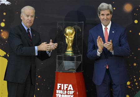 U.S. Secretary of State John Kerry (R) applauds as Vice President Joe Biden jokes that he is going to pick up the recently-unveiled FIFA World Cup Trophy, at the State Department in Washington, April 14, 2014. REUTERS/Mike Theiler