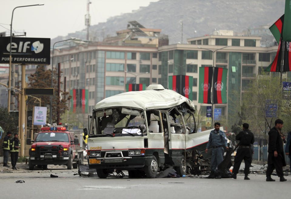 Security personnel inspect the site of a bomb attack in Kabul, Afghanistan, Monday, March 15, 2021. A bomb targeting a minibus in Afghanistan's capital exploded Monday wounding at least 15 civilians, police said, amid a surge in attacks in Kabul. (AP Photo/Rahmat Gul)