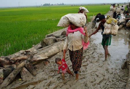 A Rohingya refugee woman holds her child as they walk on the muddy path after crossing the Bangladesh-Myanmar border in Teknaf, Bangladesh, September 3, 2017. REUTERS/Mohammad Ponir Hossain