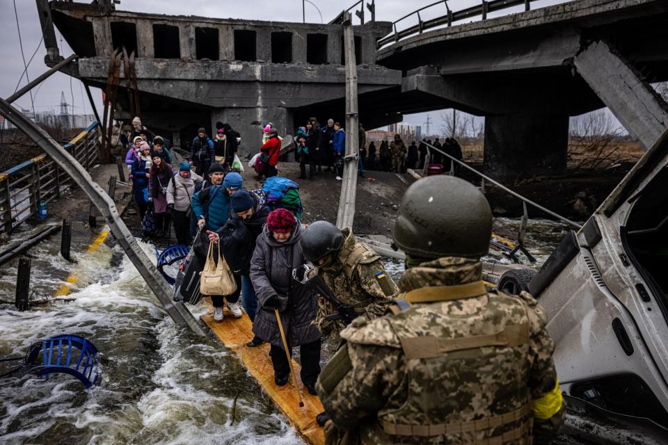 Evacuees cross a destroyed bridge as they flee the city of Irpin, northwest of Kyiv, on March 7, 2022.
