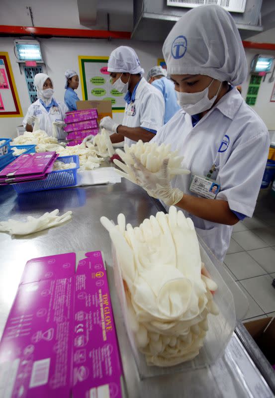 FILE PHOTO: Workers pack gloves at a Top Glove factory outside Kuala Lumpur