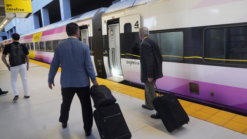 Passengers walk to board the first train service from Miami to Orlando on Friday, Sept. 22, 2023, in Miami. Brightline, which began running its neon-yellow trains between Miami and West Palm Beach in 2018, is the first private intercity passenger service to begin U.S. operations in a century.