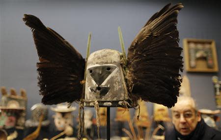 A man looks at an antique tribal mask, Tumas Crow Mother, circa 1860-1870, revered as a sacred ritual artifact by the Native American Hopi tribe in Arizona, displayed at the Drouot auction house ahead of its sale in Paris December 9, 2013. REUTERS/Christian Hartmann