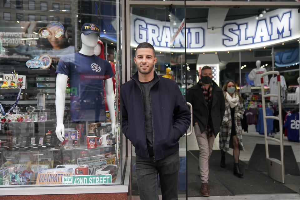 David Cohen, an owner of Grand Slam, a souvenir and sports apparel store, poses for a picture at the store in Times Square, Monday, Nov. 15, 2021, in New York. Even as visitors again crowd below the jumbo screens in New York’s Times Square, the souvenir shops, restaurants, hotels and entrepreneurs within the iconic U.S. landmark are still reeling from a staggering pandemic. (AP Photo/Seth Wenig)