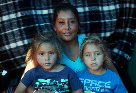 Maria Meza, a 40-year-old migrant woman from Honduras, part of a caravan of thousands from Central America trying to reach the United States, sits with her five-year-old twin daughters Cheili Mejia Meza and Saira Mejia Meza inside their tent in a temporary shelter in Tijuana, Mexico, November 26, 2018. The family was depicted in a Reuters photo of November 25 running away from tear gas. REUTERS/Hannah McKay