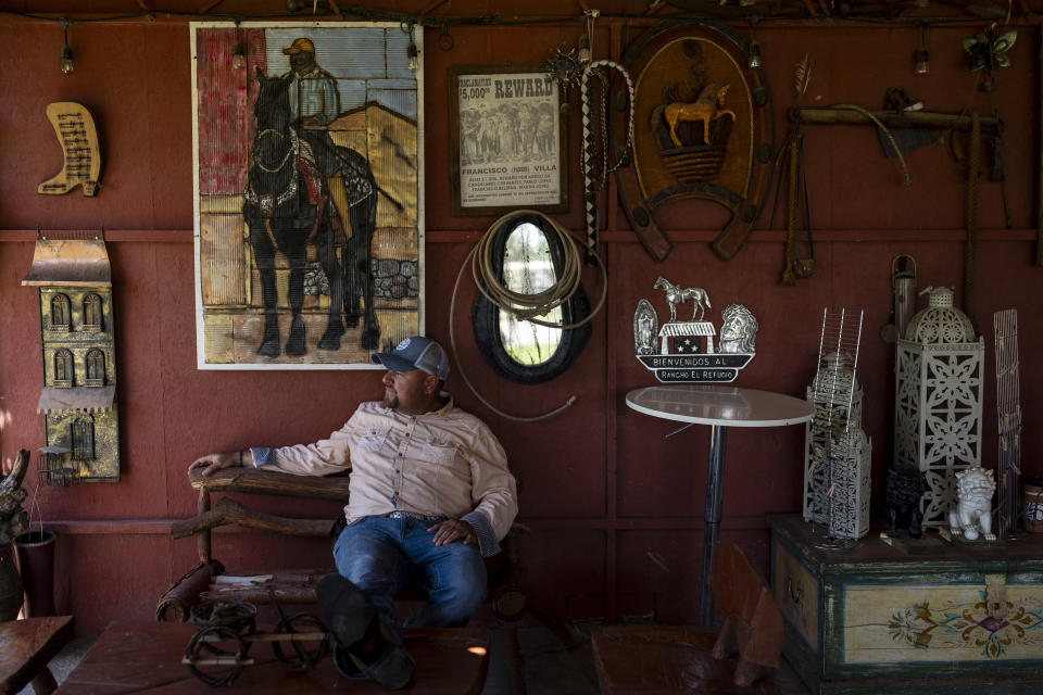 Date palm ranch owner Carlos Ulloa sits for a photo at Rancho El Refugio in Twentynine Palms, Calif., Tuesday, June 11, 2024. Ulloa's vision was to create a place where he could keep his horses and have a working ranch with sheep and peacocks while hosting events where families could have ample space to invite their relatives to a celebration without going broke. (AP Photo/Jae C. Hong)