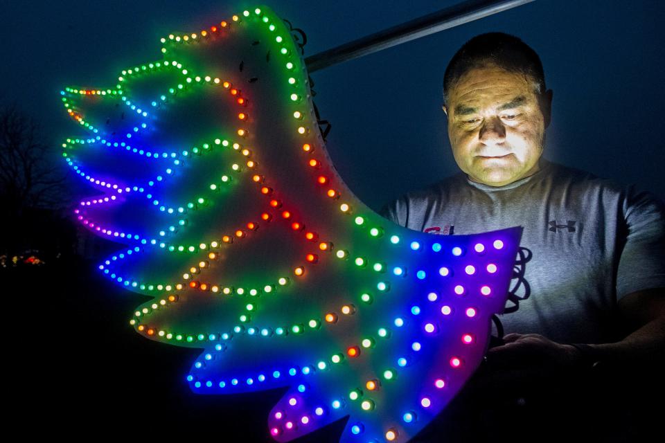 Manny Duarte makes an adjustment to a wing, part of the "photo booth" in the 31,000 Christmas lights display Duarte mounts each year outside his home in Middletown, Wednesday, Dec. 7, 2022. The interactive "photo booth" allows visitors to change the wing colors via remote control before taking their pictures.