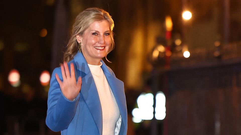 Duchess Sophie, wearing white dress and blue coat, waves at carol concert