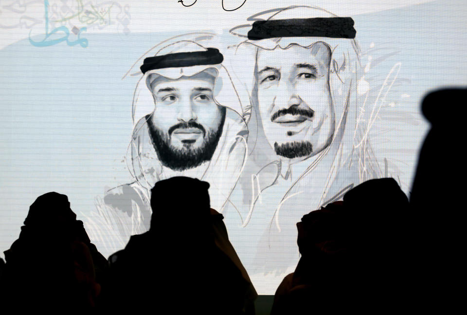 Saudi participants at the Future Investment Initiative, "FII" stand to greet the national anthem in front of a screen displaying images of Saudi King Salman, right, and Crown Prince Mohammed bin Salman, a day before it will be held in Riyadh, Saudi Arabia, Monday, Oct. 28, 2019. The FII, is an annual investment forum held in Riyadh, to discuss trends in the world economy and investment environment hosted by the Public Investment Fund of Saudi Arabia. (AP Photo/Amr Nabil)