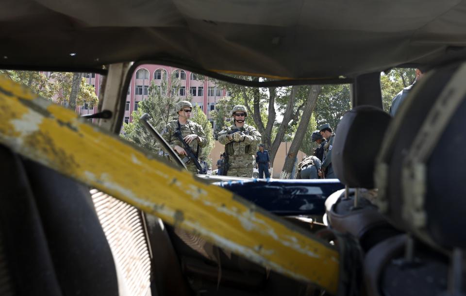 U.S. troops keep watch near a damaged vehicle at the site of a suicide attack in Kabul September 16, 2014. (REUTERS/Mohammad Ismail)