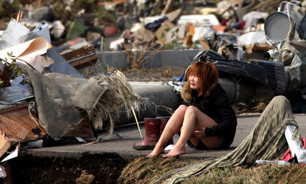 A woman reacts amidst debris caused by the massive 9.0-magnitude earthquake-triggered tsunami on March 13, 2011, in Natori, northern Japan. The earthquake struck Japan’s offshore on March 11, at 2:46 pm local time, triggering a tsunami wave of up to 10 metres which engulfed large parts of the north east and also damaging the Fukushima nuclear plant, causing the worst nuclear crisis in decades. The current number of dead and missing is estimated to be 22,900. (AP Photo/Asahi Shimbun, Toshiyuki Tsunenari)