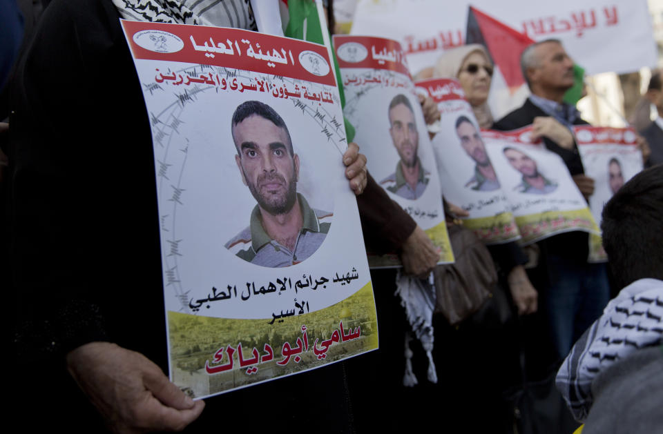 Protesters fly Palestinian flags and carry posters with pictures of Palestinian prisoner in Israeli jail, Sami Abu Diak, who died this morning, during a protest in the West Bank city of Ramallah, Tuesday, Nov. 26. 2019. Diak died Tuesday in Israeli custody after battling cancer, Israel's prisons service said, ahead of demonstrations in the West Bank planned before his death. Aranic in the poster reads: "The Martyr of the Israeli medical neglect crimes, Sami Abu Diak."(AP Photo/Nasser Nasser)
