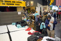 People select shirts and sweatshirts being given away at a Gallery Furniture store after the owner opened his business as a shelter for those without power at their homes Tuesday, Feb. 16, 2021, in Houston. More than 4 million people in Texas still had no power a full day after historic snowfall and single-digit temperatures created a surge of demand for electricity to warm up homes unaccustomed to such extreme lows, buckling the state's power grid and causing widespread blackouts. (AP Photo/David J. Phillip)