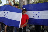 Migrantes hondureños que intentan llegar a Estados Unidos muestran banderas hondureñas tras ser detenidos por la Policía Nacional guatemalteca después de cruzar la frontera con Honduras, en Morales, Guatemala, el 15 de enero de 2020. (AP Foto/Moisés Castillo)