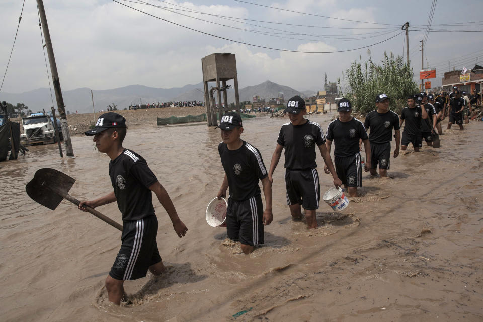 Soldiers carry tools to use for helping neighbors cross a flooded street in Lima, Peru, Thursday, March 16, 2017. A new round of unusually heavy rains has killed at least a dozen people in Peru and now threatens flooding in the capital. Authorities said Thursday they expect the intense rains caused by the warming of surface waters in the eastern Pacific Ocean to continue another two weeks. (AP Photo/Rodrigo Abd)