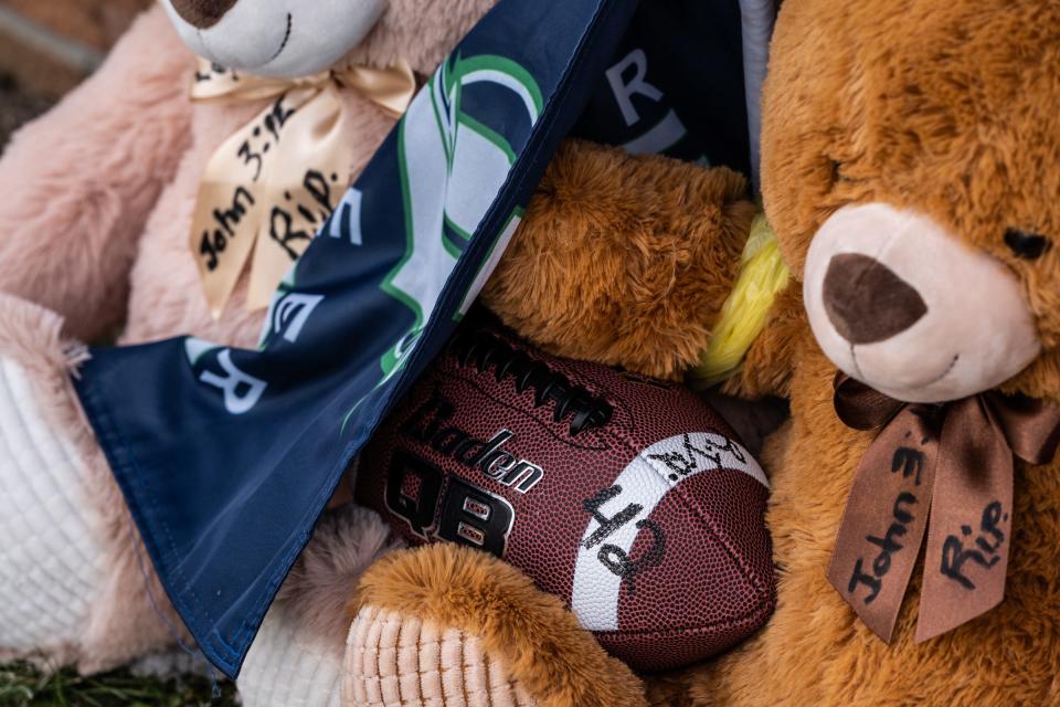 Stuffed animals and a football are left amongst bouquets of flowers and other items at an entrance to Oxford High School on Dec. 1, 2021, following an active shooter situation at Oxford High School that left four students dead and multiple others with injuries.