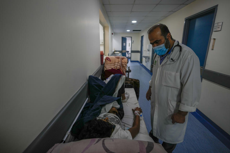 Doctor Jihad Bikai checks on a patient who is lies in a bed at crowded government-run Rafik Hariri University Hospital corridor in Beirut, Lebanon, Wednesday, Aug. 11, 2021. Many private hospitals, who offer 80% of Lebanon's medical services, are shutting down because of lack of resources or turning away patients who can't pay. (AP Photo/Hassan Ammar)