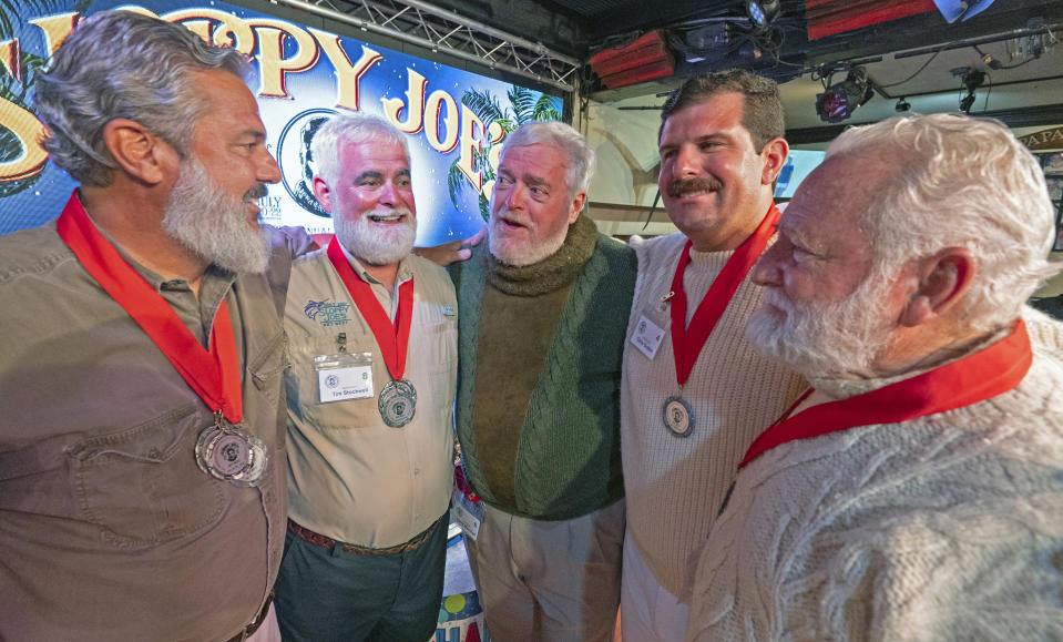 In this Saturday, July 22, 2023, photo provided by the Florida Keys News Bureau, finalists in the 2023 Hemingway Look-Alike Contest including, from left, Paul Phillips, Tim Stockwell, Gerrit Marshall, Chris Dutton and Bat Masterson, converse with each other while awaiting the judges' results at Sloppy Joe's Bar in Key West, Fla. The competition was a highlight of the annual Hemingway Days festival that ends Sunday, July 23. Ernest Hemingway lived in Key West throughout most of the 1930s. After 11 years of competing, Marshall, a Madison, Wisc., resident, achieved success on his 68th birthday. (Andy Newman/Florida Keys News Bureau via AP)