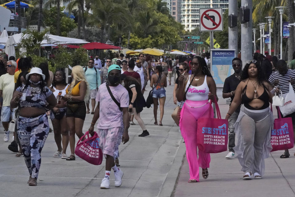 People in a mostly maskless crowd walk down Ocean Drive in Miami Beach, Florida's famed South Beach, Monday, March 22, 2021. A party-ending curfew is in effect in Miami Beach, imposed after fights, gunfire, property destruction and dangerous stampedes broke out among huge crowds of people. The curfew could extend through the end of spring break. (AP Photo/Wilfredo Lee)