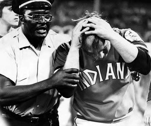 A security guard escorts Cleveland pitcher Tom Hilgendorf after he was hit on the head with a folding chair during the fan riot on 10-cent beer night on June 4, 1974, at Cleveland Stadium. Umpire crew chief Nestor Chylak declared the game a forfeit victory for Texas.