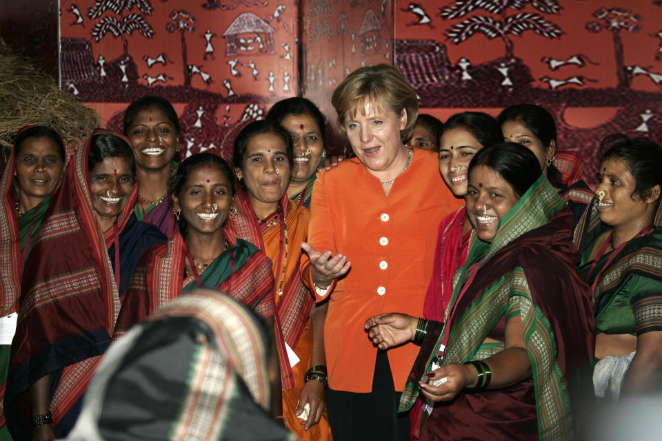 FILE - In this Wednesday, Oct. 31, 2007, file photo, German Chancellor Angela Merkel, center, asks a woman, front, to join a group photo with Indian country women during her visit to the NABARD-Bank in Mumbai, India. On trips to Africa, the Middle East and Asia, Merkel has often made a point of visiting women’s rights projects. She has always stressed that giving women in poor countries better access to education and work is key to those nations' development. (AP Photo/Herbert Knosowski, File)