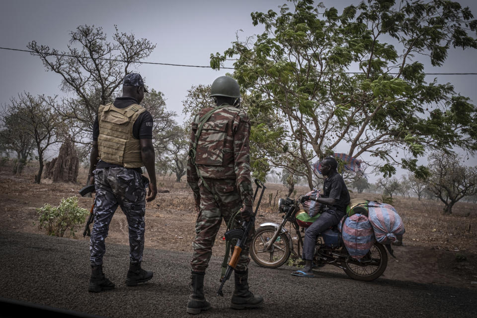 FILE - A police officer and a soldier from Benin stop a motorcyclist at a checkpoint outside Porga, Benin, March 26, 2022. Groups linked to al-Qaida and the Islamic State have been spreading from the vast, arid expanse south of the Sahara Desert into wealthier nations on the coast of West Africa. The jihadis' activity in Benin is concentrated in the north of the country, and people there live in constant fear because of the jihadi threat. (AP Photo/Marco Simoncelli, File)