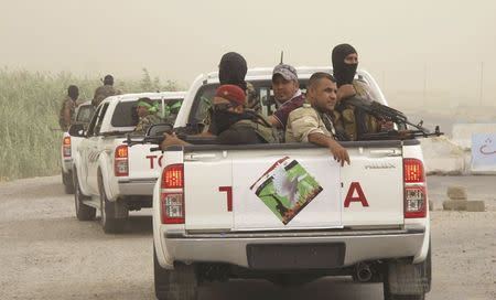 Armed Shi'ite volunteers from brigades loyal to radical cleric Muqtada al-Sadr, sit in the back of vehicles during a patrol after clashes with militants of the Islamic State, formerly known as the Islamic State in Iraq and the Levant (ISIL), on the outskirts of Samarra in Salahuddin province July 13, 2014. REUTERS/Stringer