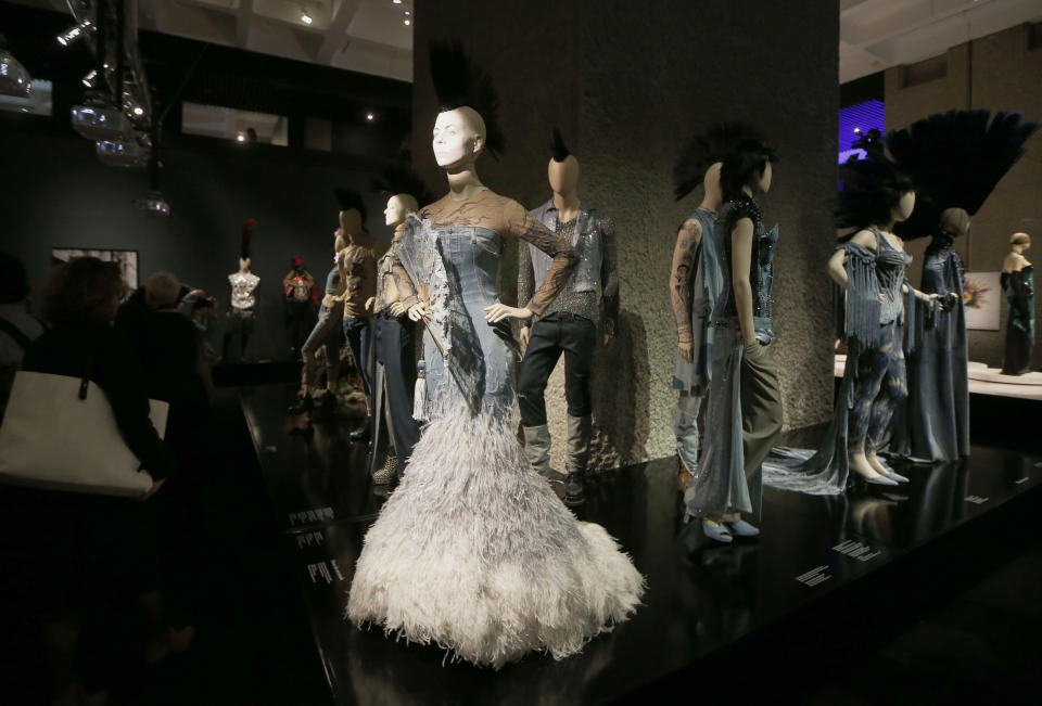 Visitors look at the creations of French couturier Jean Paul Gaultier during the launch his exhibition 'The Fashion World of Jean Paul Gaultier : From the Sidewalk to the Catwalk' at the Barbican Art Gallery in London, Tuesday, April 8, 2014. (AP Photo/Sang Tan)