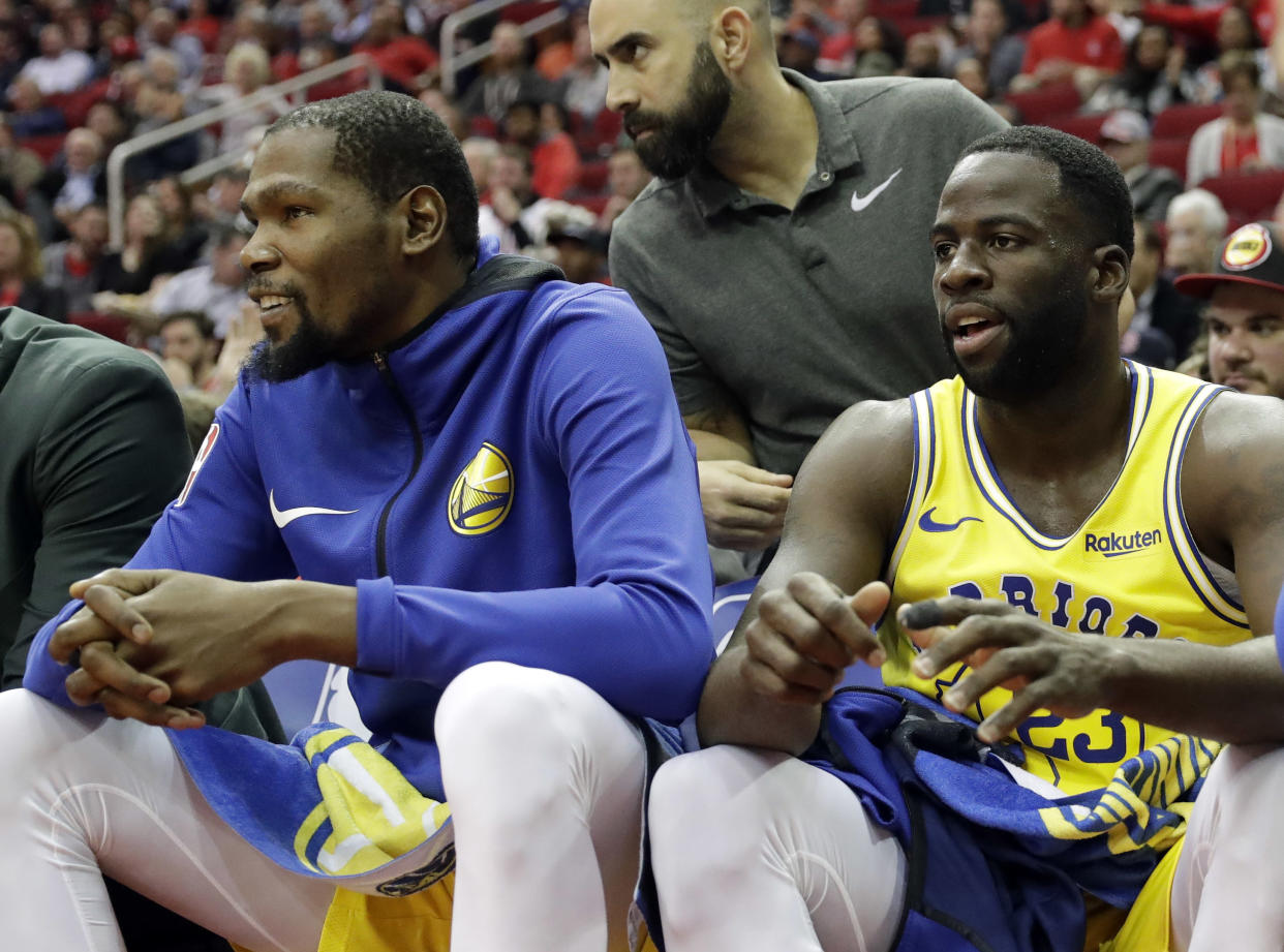 Kevin Durant and Draymond Green sit together on the bench during the first half Thursday night during a loss to the Rockets. (AP)