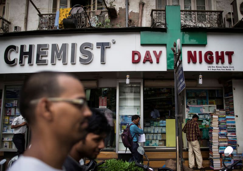 FILE PHOTO: FILE PHOTO: People walk past a chemist shop at a market in Mumbai