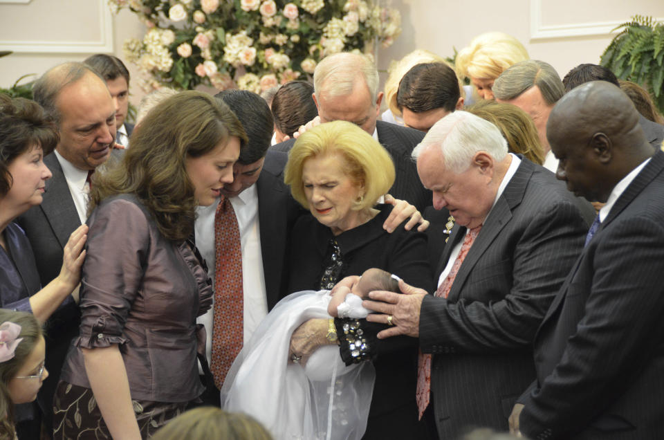 In this 2012 photo provided by a former member of the church, Word of Faith Fellowship leader Jane Whaley, center, holds a baby, accompanied by her husband, Sam, center right, and others during a ceremony in the church's compound in Spindale, N.C. From all over the world, they flocked to this tiny town in the foothills of the Blue Ridge Mountains, lured by promises of inner peace and eternal life. What many found instead: years of terror _ waged in the name of the Lord. (AP Photo)