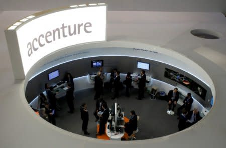 FILE PHOTO: Visitors look at devices at Accenture stand at the Mobile World Congress in Barcelona, February 26, 2013. REUTERS/Albert Gea/File Photo