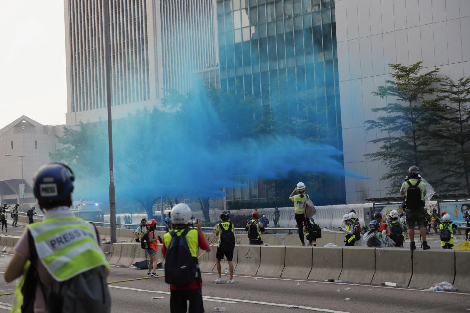 Police vehicle sprays blue-colored water towards anti-government protesters during a demonstration near Central Government Complex in Hong Kong, Sunday, Sept. 15, 2019. Police fired a water cannon and tear gas at protesters who lobbed Molotov cocktails outside the Hong Kong government office complex Sunday, as violence flared anew after thousands of pro-democracy supporters marched through downtown in defiance of a police ban. (AP Photo/Kin Cheung)