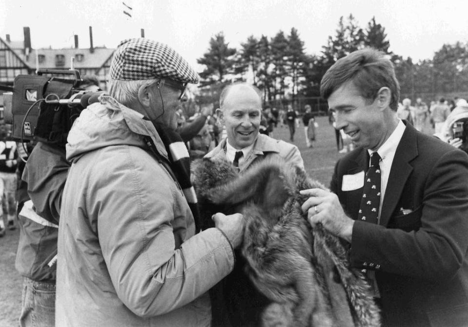 Groton alum and former Mass. Governor Endicott "Chub" Peabody presents the Raccoon Coat to St. Mark's headmaster Chris Mabley for the first time in 1989. SM just won the 100th football game against Groton. Groton headmaster Bill Polk looks on.