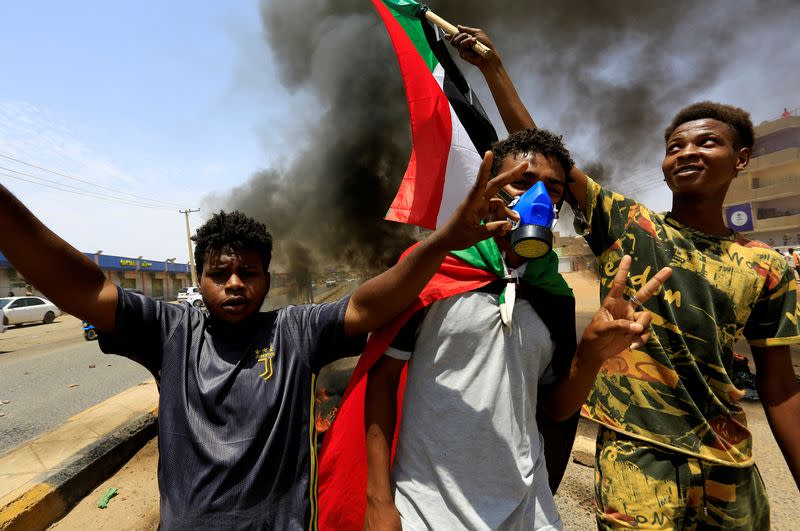 FILE PHOTO: Civilians with the national flags gestures at a barricade as members of Sudanese pro-democracy group demonstrate on the anniversary of a major anti-military protest, as groups loyal to toppled leader Omar al-Bashir plan rival demonstrations in