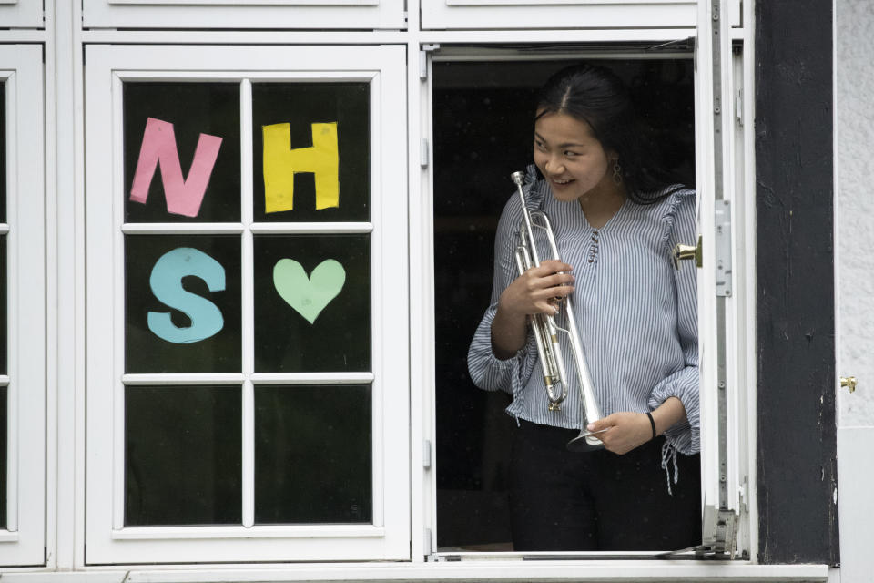 National Youth Orchestra of Great Britain trumpet player Tian Hsu, 16, gives a dedication for a video her family was recording just before taking part in a socially distanced orchestra performance of Beethoven's "Ode to Joy" from a window of her home in south west London, during the lockdown to prevent the spread of coronavirus, Friday, April 17, 2020. The members of the National Youth Orchestra, took part in the coordinated Ode to Joy-a-thon on Friday, each giving their own 40 second performance, with photos or videos taken by their families to share on social media. They dedicated the performance to the National Health Service staff, key workers, and people who feel isolated in their homes during the lockdown. (AP Photo/Matt Dunham)