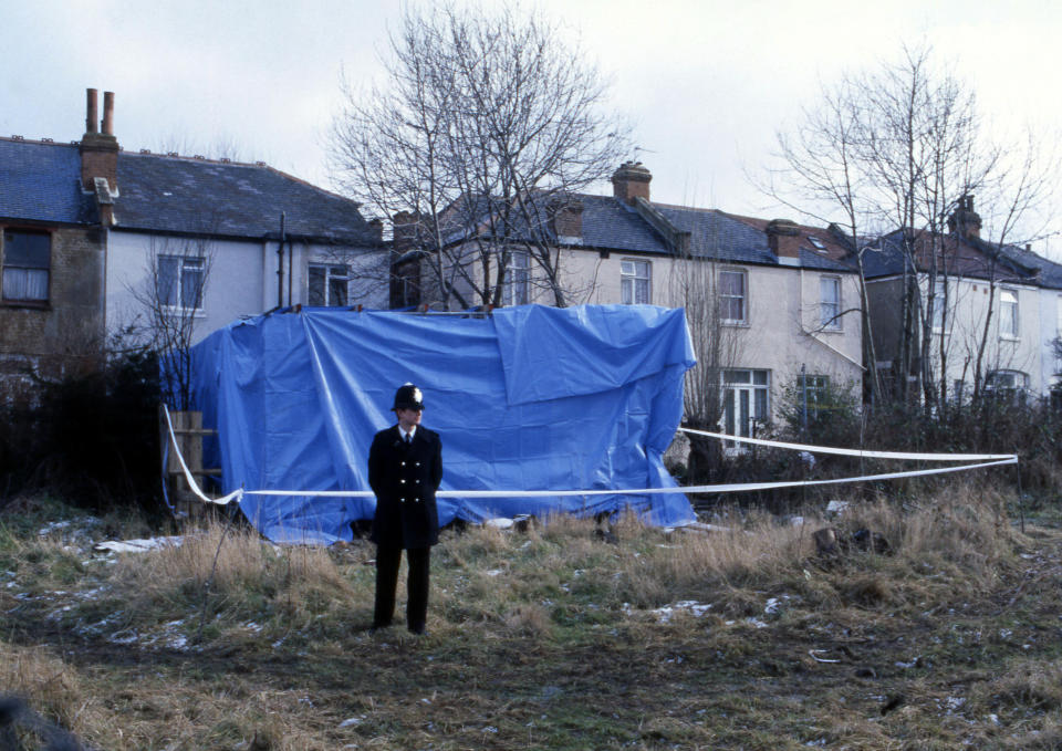 A London policeman stands guard near a canopy erected on the garden of the North London home of Dennis Nilsen, on Feb. 13, 1983, as policemen inside dig the soil in search of the remains of human bodies believed to have been buried there. Police say there could be the remains of up to 13 murder victims buried in the area. The house is in Melrose Avenue, Willesden Green. (AP Photo/John Redman)