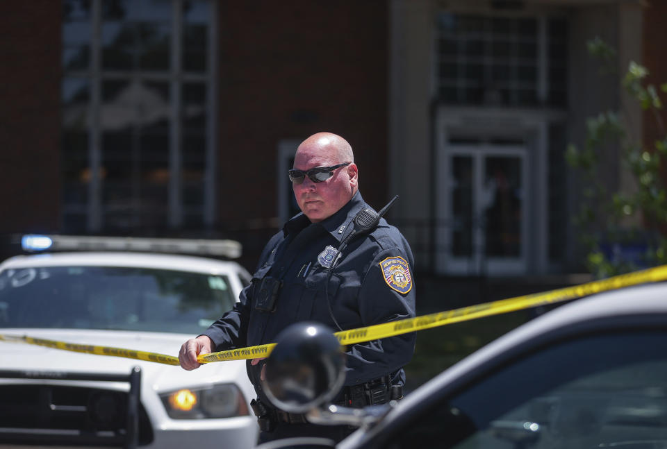 A Memphis Police officer extends crime scene tape around the perimeter of an active shooter situation near the University of Memphis, Tuesday, May 2, 2023. A Memphis television station says a shot was fired at its building, but no one was wounded. WHBQ, the Fox affiliate in Tennessee’s second-largest city, reported that the shot was fired and that the bullet fell outside of the front door of the lobby of the building, which is located in a commercial area near the University of Memphis campus. (Patrick Lantrip/Daily Memphian via AP)