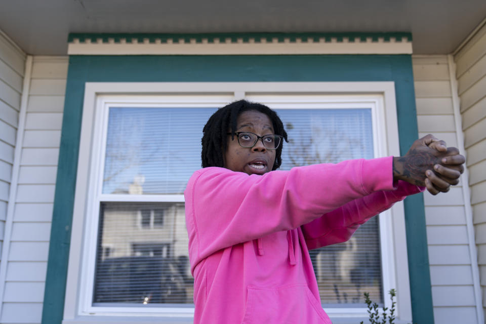 Briana Tyler speaks with The Associated Press and uses her hands like a gun as she demonstrates the gunman shooting indiscriminately, as she talks about witnessing the mass shooting at a Walmart, Wednesday, Nov. 23, 2022, in Chesapeake, Va. Tyler said the overnight stocking team of about 15 or 20 people had just gotten together in the break room to go over the morning plan. As soon as the team was set to start, she said she looked up, and her manager turned around and opened fire on the staff. (AP Photo/Alex Brandon)