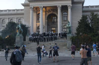 Riot police start a charge at protestors on the steps of the Serbian parliament during a protest in Belgrade, Serbia, Wednesday, July 8, 2020. Police have fired tear gas at protesters in Serbia's capital during the second day of demonstrations against the president's handling of the country's coronavirus outbreak. President Aleksandar Vucic backtracked on his plans to reinstate a coronavirus lockdown in Belgrade this week, but it didn't stop people from firing flares and throwing stones while trying to storm the downtown parliament building. (AP Photo/Marko Drobnjakovic)