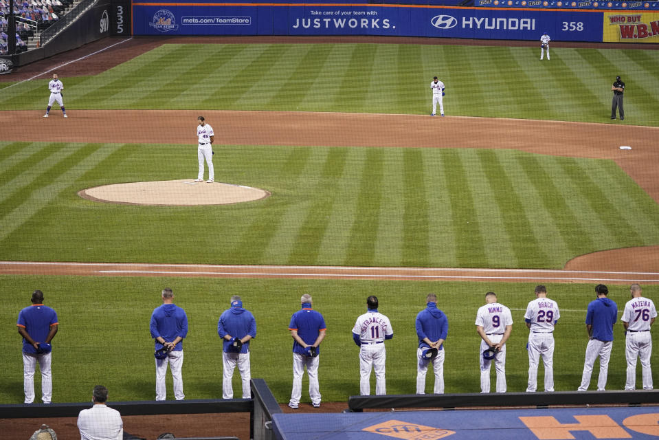 The New York Mets and Miami Marlins stand on the field and bow their heads before a scheduled baseball game Thursday, Aug. 27, 2020, in New York. Mets outfielder Dominic Smith — a Black man who wept Wednesday night discussing the shooting by police of a Black man in Wisconsin over the weekend — led New York onto the field. Players took their positions, then reserves and coaches filed out of both dugouts and stood silently for 42 seconds. Both teams then left the field, leaving only the black T-shirt at home. (AP Photo/John Minchillo)