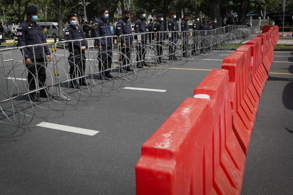 Police stand guard behind barricades and razor wire as anti-government protesters rally near the Democracy Monument in Bangkok, Thailand, Wednesday, Oct. 14, 2020. Anti-government protesters began gathering Wednesday for a planned rally at Bangkok's Democracy Monument being held on the anniversary of a 1973 popular uprising that led to the ousting of a military dictatorship, amid a heavy police presence and fear of clashes with political opponents. (AP Photo/Sakchai Lalit)