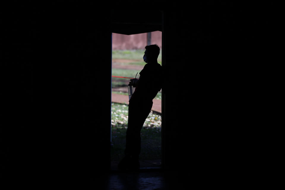 A youth living in quarantine drinks "mate," a traditional herbal drink as he peers from the door of a gym at a school being used as a government-run shelter where citizens returning home are required by law to quarantine for two weeks and pass two consecutive COVID-19 tests, as a preventive measure amid the COVID-19 pandemic in Ciudad del Este, Paraguay, Wednesday, June 24, 2020. Some 8,500 have passed through the quarantine system already. (AP Photo/Jorge Saenz)