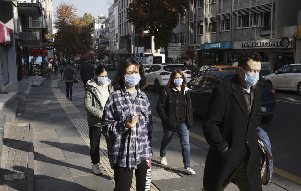 People wearing masks to help protect against the spread of coronavirus, walk, in Ankara, Turkey, Monday, Nov. 15, 2020. Turkish health ministry statistics show 93 people died Friday of COVID-19 amid a surge in infections, bringing the daily death toll to numbers last seen in April.(AP Photo/Burhan Ozbilici)