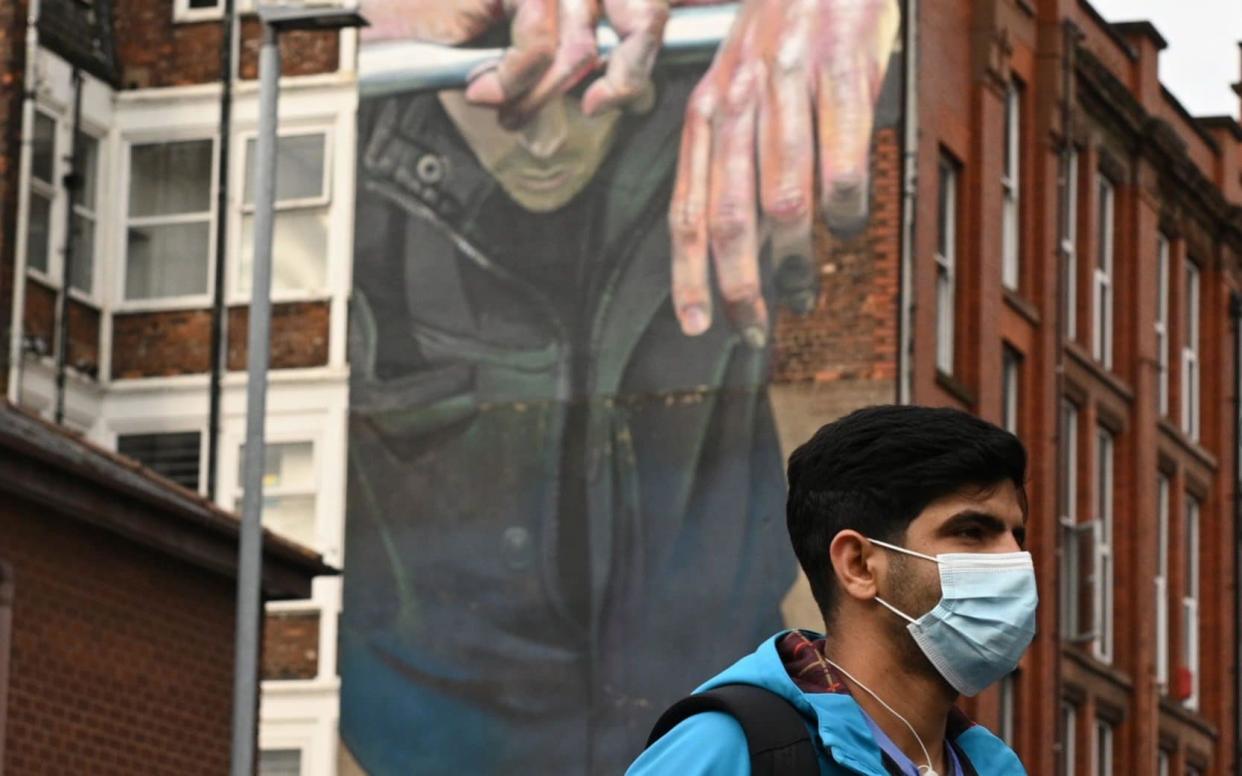 A man walks past a mural in Manchester - Oli Scarff/AFP