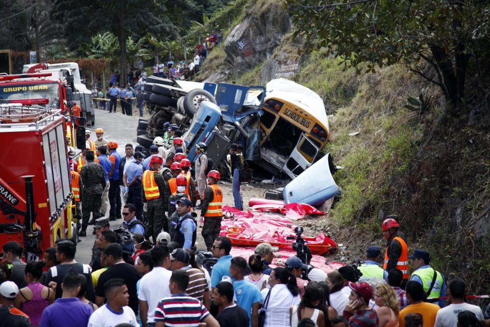 Emergency personnel respond to an accident involving a cargo truck and bus on the outskirts of Tegucigalpa, Honduras, Sunday, Feb. 5, 2017. The cargo truck crashed into the bus on the highway outside Honduras' capital Sunday, killing more than a dozen people, authorities said. Police said the truck driver fled after the crash on a highway that links the capital with southern Honduras. (AP Photo/Fernando Antonio)